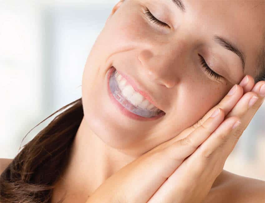 Woman sleeping with a night guard for bruxism, using hands as pillow demonstration