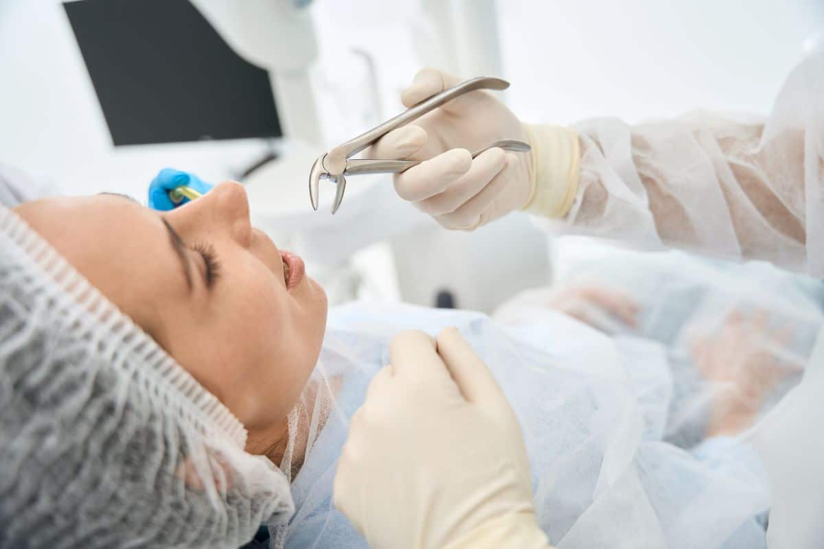 Dentist preparing dental extraction tools during oral surgery procedure