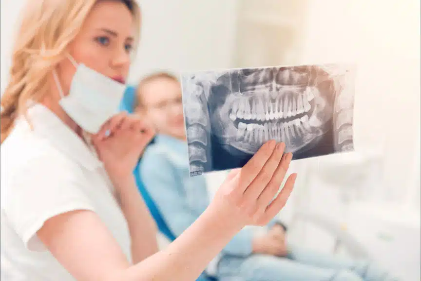 Dentist examining a panoramic dental X-ray to evaluate wisdom teeth positioning and identify potential impaction before symptoms develop.